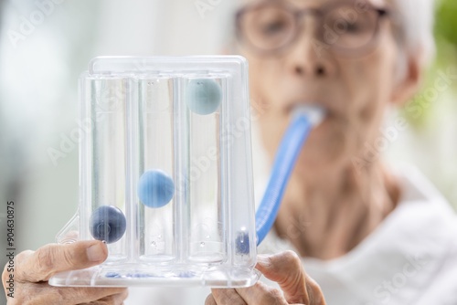 Canvas Print Asian senior woman using incentive spirometer,tool to help the lung expansion,ex