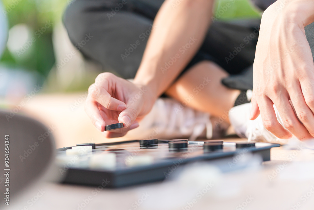 Close up of Asian teenage boy hand and girl playing board game, Asian brother and sister relaxing hobbies playing a game of checkers outdoor Close up of Asian teenage boy hand and girl playing board game, Asian brother and sister relaxing hobbies playing a game of checkers outdoor