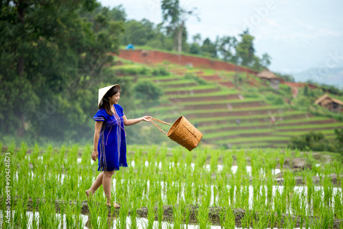 Wallpaper Mural Woman in blue traditional hmong dress and straw hat walking with basket in terraced rice field with green hills and village in background Torontodigital.ca