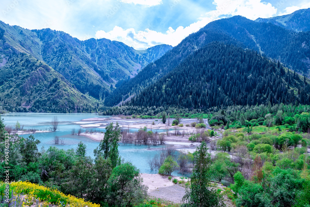 Fototapeta premium Lake Issyk, Almaty, Kazakhstan. Very beautiful landscape. Mountain lake with blue water against a background of mountains and trees with green grass