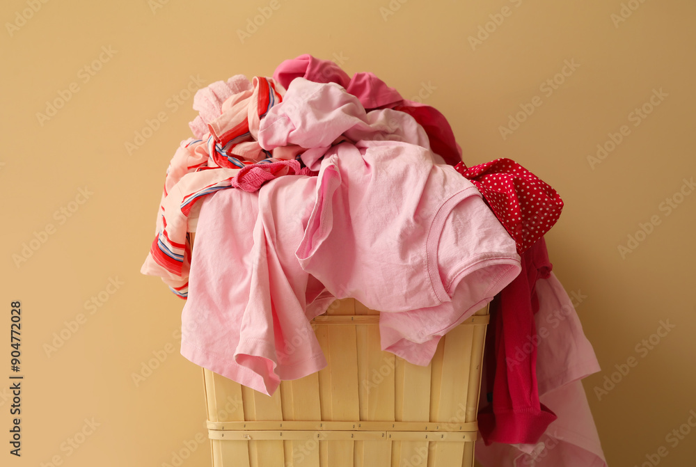 Basket with dirty clothes near beige wall, closeup Basket with dirty clothes near beige wall, closeup