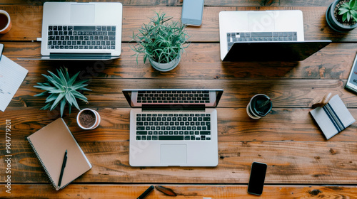 Stylish workspace with laptops, plants, and stationery on a wooden desk, perfect for remote work and creativity. photo