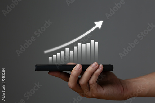 Businessman holding a smartphone or mobile phone with a business growth diagram business economics technology concept