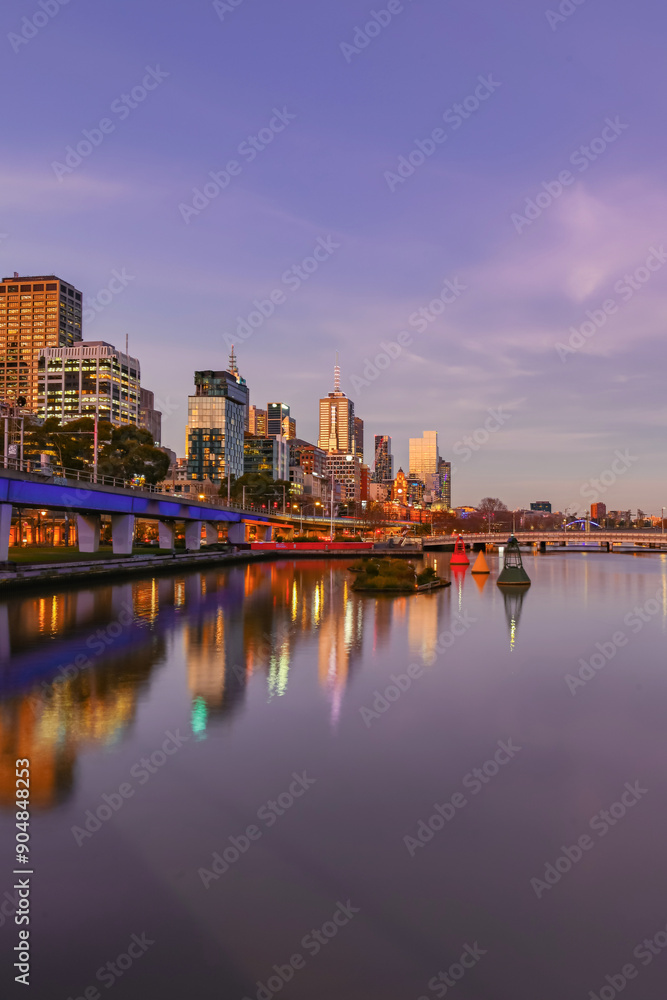 Fototapeta premium Melbourne's City Skyline behind the Yarra River during a pink Sunset in Australia during winter. 
