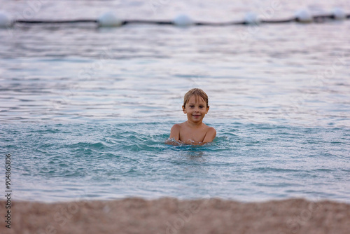 Child, swimming in the sea summertime in Monaco, happily splashing water