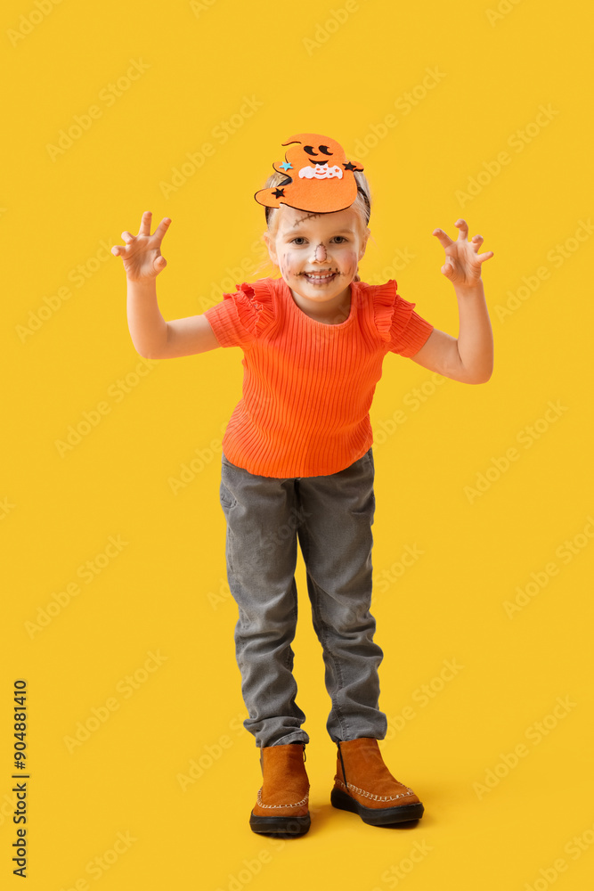 Little girl dressed for Halloween on yellow background Little girl dressed for Halloween on yellow background