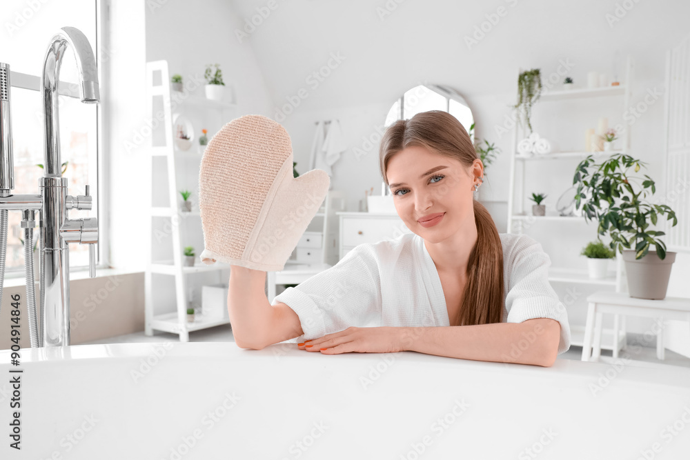 Young woman with massage glove near bathtub at home Young woman with massage glove near bathtub at home