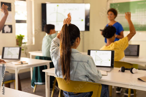 Fotografie In high school, students raising hands and using laptops during classroom lesson