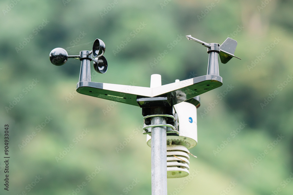 A close-up of weather station equipment used for measuring wind and other weather conditions, set against a natural green background A close-up of weather station equipment used for measuring wind and other weather conditions, set against a natural green background