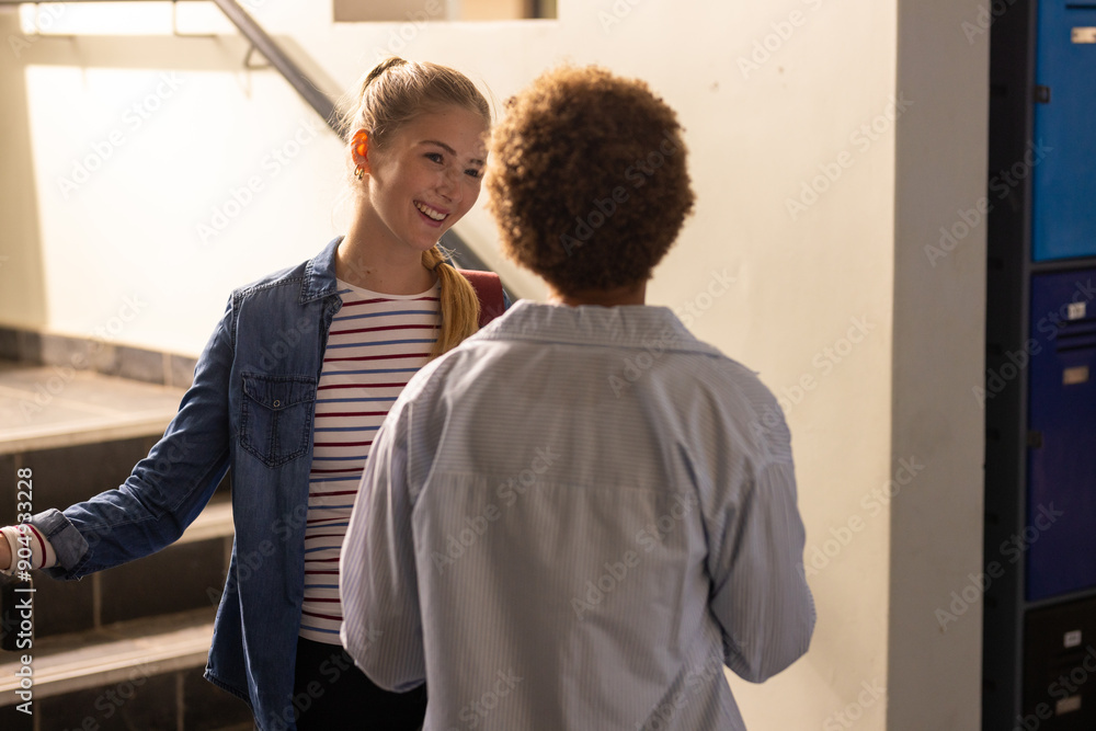 In high school, teenagers talking and smiling in hallway near lockers In high school, teenagers talking and smiling in hallway near lockers
