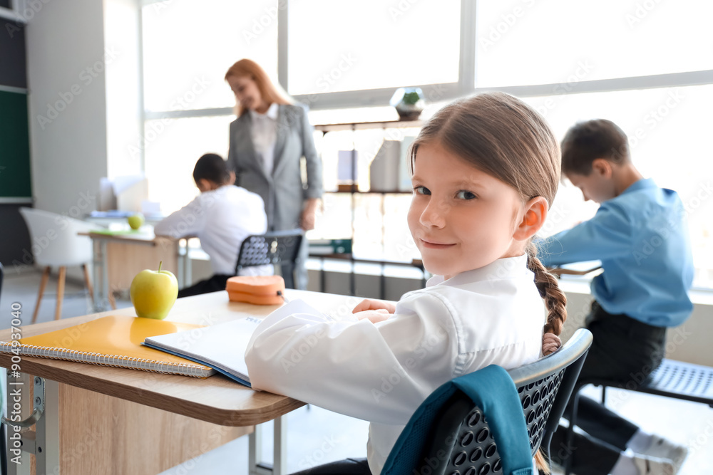 Obraz premium Little schoolgirl having lesson in classroom, closeup