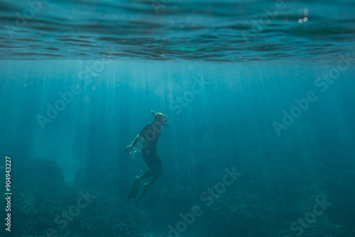 Male snorkeler swims to the surface of the ocean photo