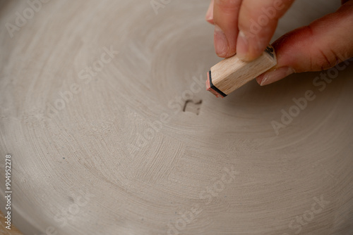 Decorating clay products with special patters and symbols on a ceramics workshop. Using a clay stamp to engrave letters and ornaments on a pottery project. photo