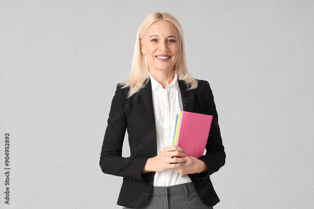 Mature female teacher with copybooks on light background Mature female teacher with copybooks on light background