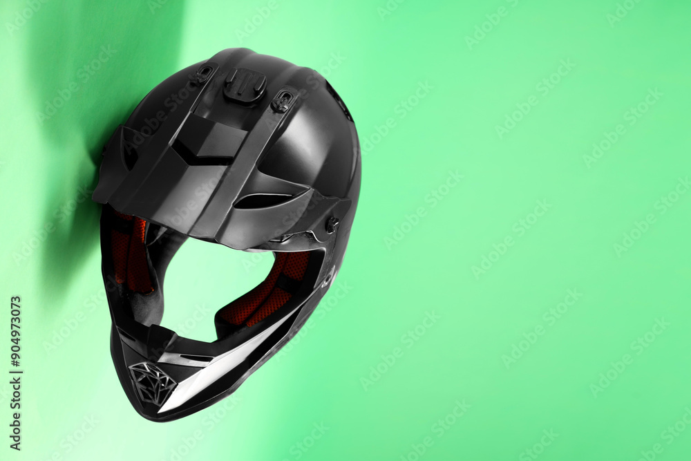 Fototapeta premium Modern motorcycle helmet with visor on light green background. Space for text