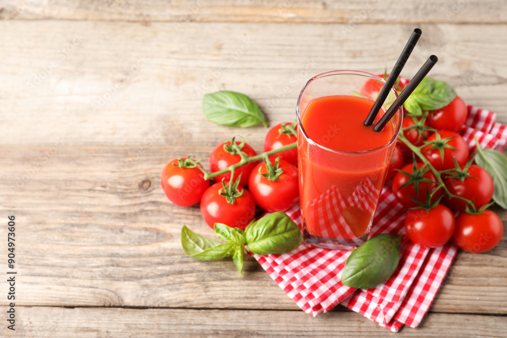 Tasty tomato juice in glass with basil leaves and fresh vegetables on wooden table, space for text Tasty tomato juice in glass with basil leaves and fresh vegetables on wooden table, space for text
