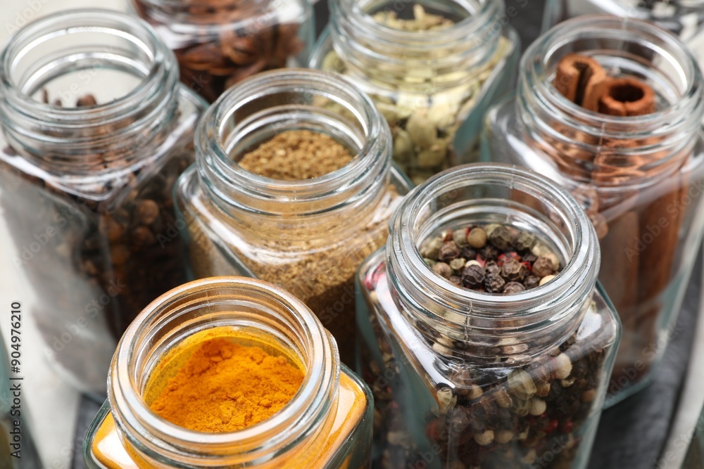 Different spices in glass jars on table, closeup Different spices in glass jars on table, closeup