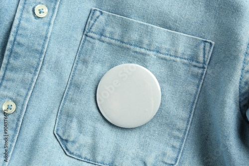 Foto White button badge pinned on denim shirt, top view