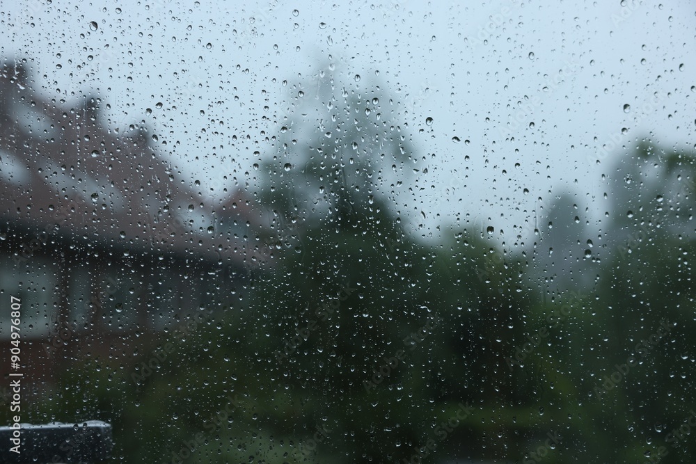 View on buildings through window with water droplets on rainy day, closeup View on buildings through window with water droplets on rainy day, closeup