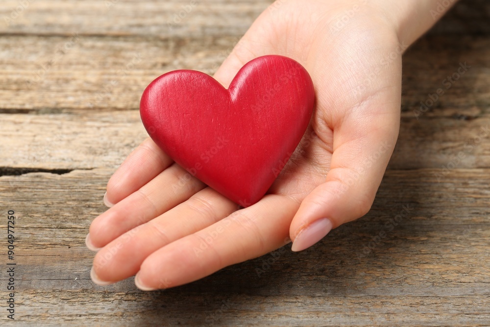 Woman with red decorative heart at wooden table, closeup Woman with red decorative heart at wooden table, closeup
