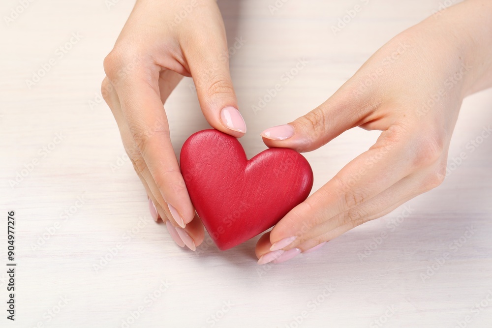 Woman with red decorative heart at white wooden table, closeup