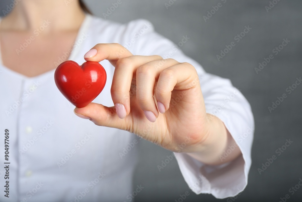 Doctor holding red heart on grey background, closeup Doctor holding red heart on grey background, closeup