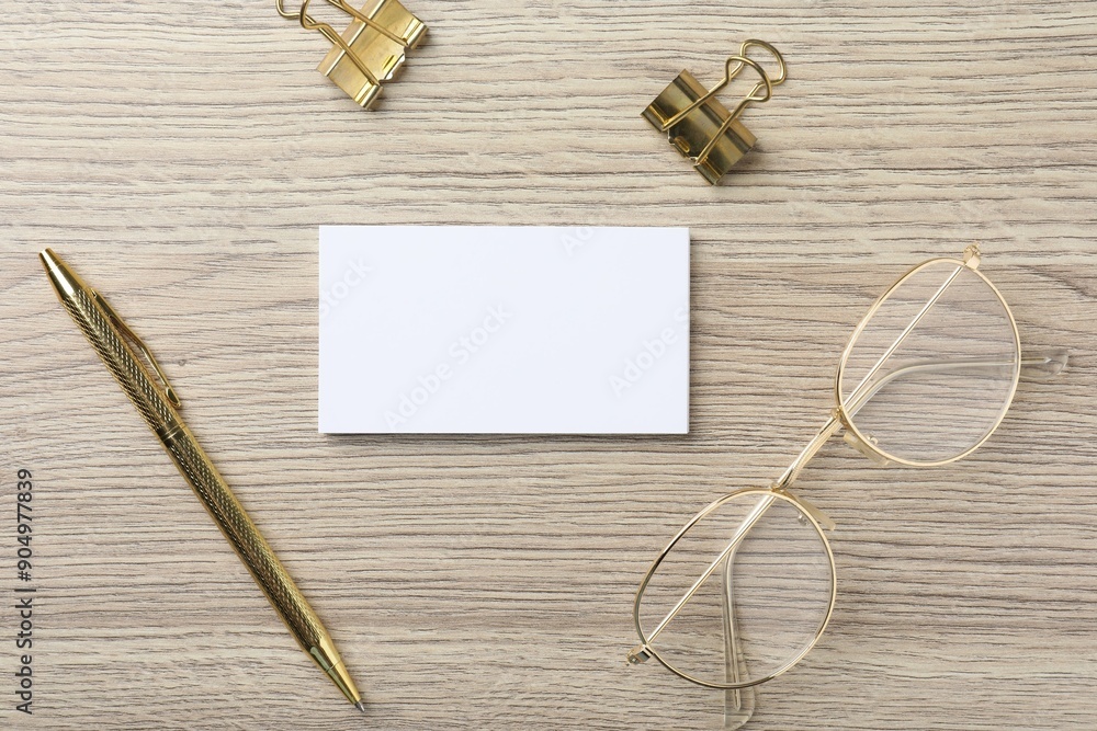 Blank business cards, glasses, golden pen and binder clips on wooden table, flat lay. Mockup for design Blank business cards, glasses, golden pen and binder clips on wooden table, flat lay. Mockup for design