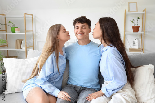 Fotografía Young man with two women kissing on sofa at home
