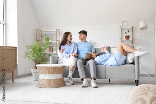 Young man with two women resting on sofa at home. Polyamory concept photo