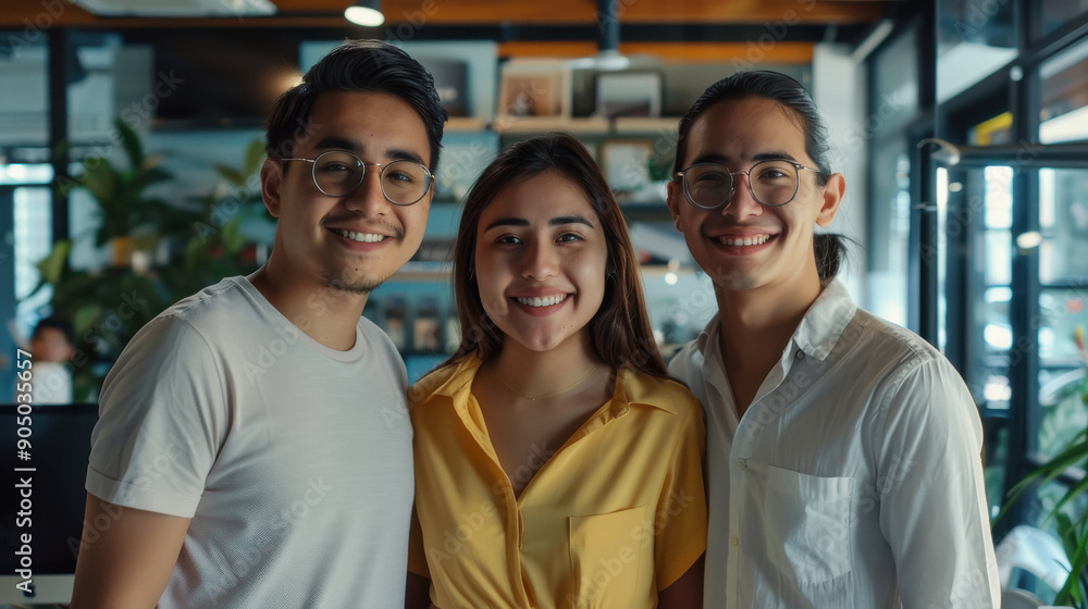 mexican coworkers standing together in the office smiling.
