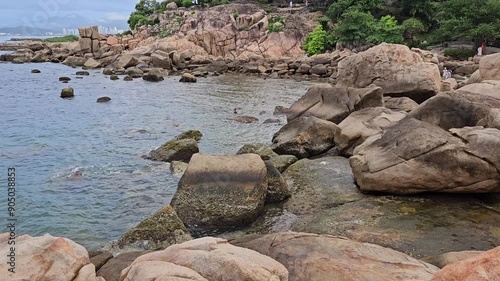 4k pan tilt a Hon Chong cape rock garden by the sea. Tourists travel walking on huge coastal boulders in Hon Chong rock garden in Nha Trang city, Vietnam. photo