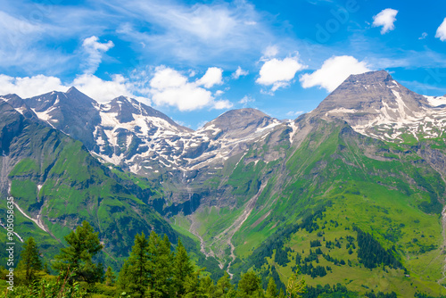 Majestic mountain landscape in summer with lush greenery and blue sky with clouds.