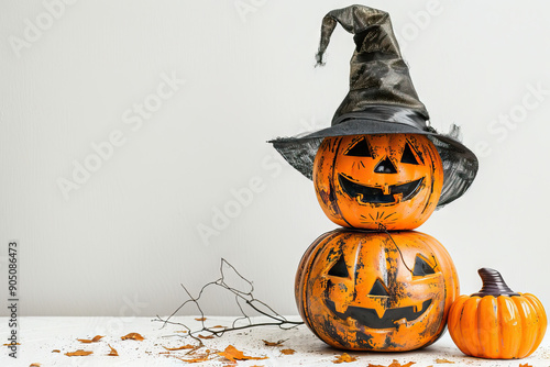 Festive Halloween display featuring a jack-o'-lantern wearing a witch hat on a table, adorned with autumn leaves.