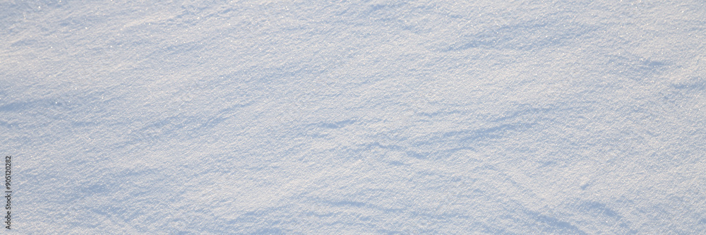 Beautiful winter background with snowy ground. Natural snow texture. Wind sculpted patterns on snow surface. Wide panoramic texture for background and design.
