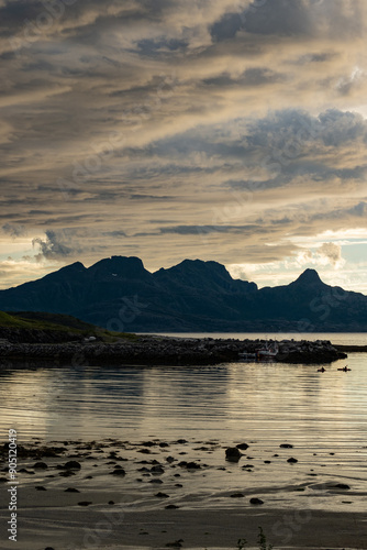 Dramatic evening storm clouds at stunning evening over the beach at Mjelle in Northern Norway pouring rain over the bay