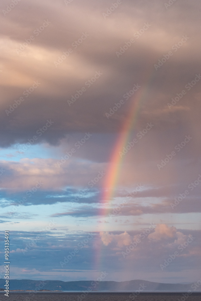 Rainbow coming out of stormy clouds under the rain Rainbow coming out of stormy clouds under the rain
