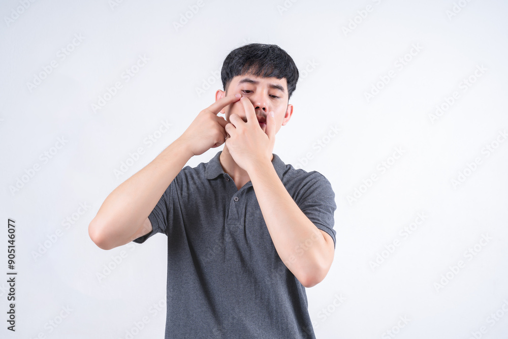 Portrait of handsome Asian man squeezing pimples on his face. Medical and healthcare concept on white background. Portrait of handsome Asian man squeezing pimples on his face. Medical and healthcare concept on white background.