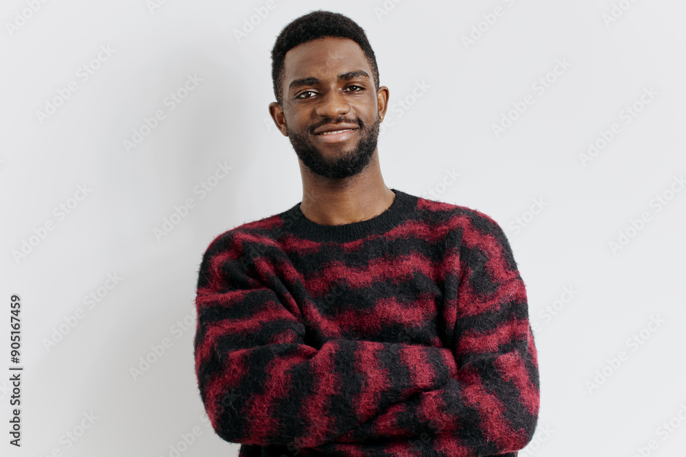 Obraz premium Confident young man in stylish red and black sweater standing against a plain white background