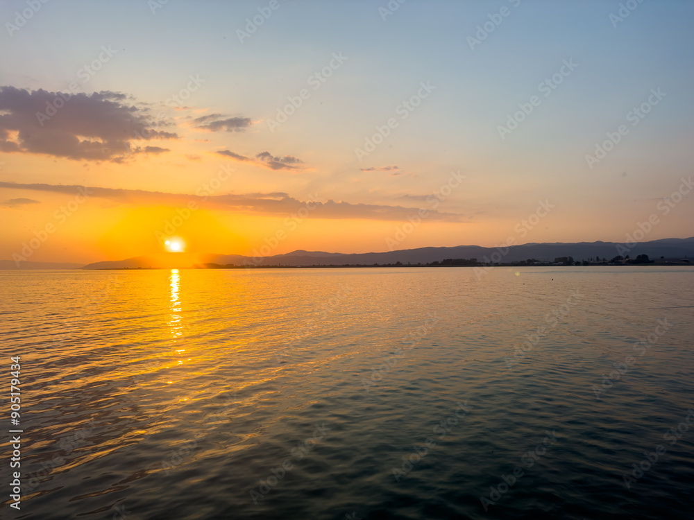Obraz premium A group of adult friends are standing on the pier by the sea at sunset, friendship themed concept