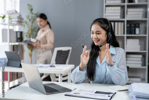 A woman wearing a headset is talking on a laptop