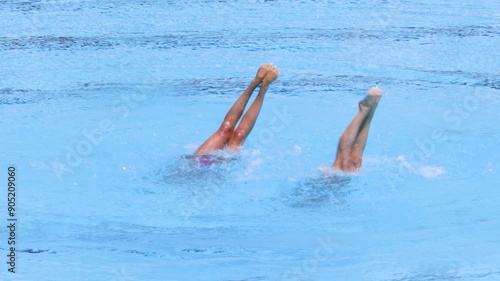 Synchronized or artistic swimming duet performing synchronized legs movement in swimming pool