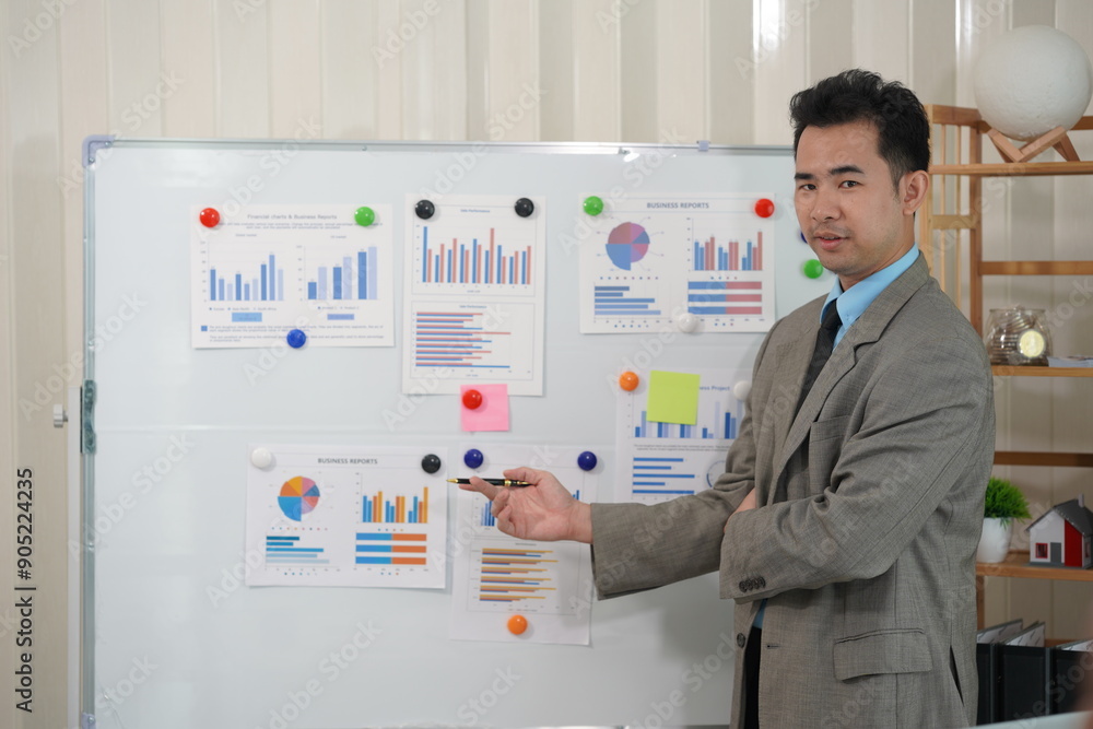 Fototapeta premium Asian male accountant working on table calculating taxes from annual financial documents, analyzing company budget report graphs. Assigned accounts receivable production control