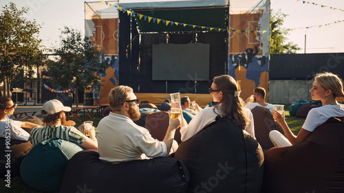 Photography Group of people, men and women, friends gathering outdoor to watch movie on warm summer day, drinking beer and relaxing