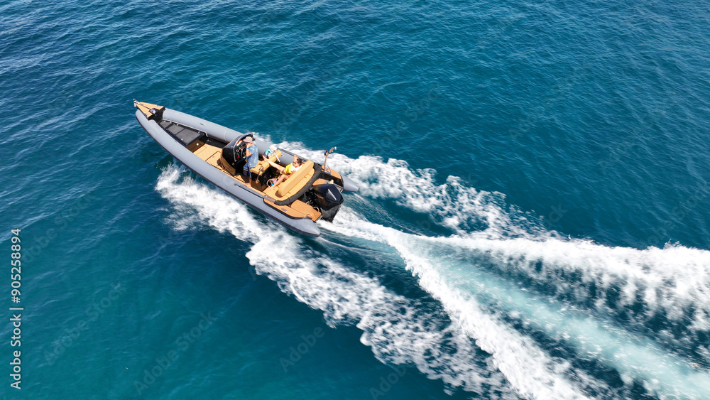 Aerial drone high speed tracking shot of inflatable rigid power boat cruising in high speed in Mediterranean deep blue sea bay