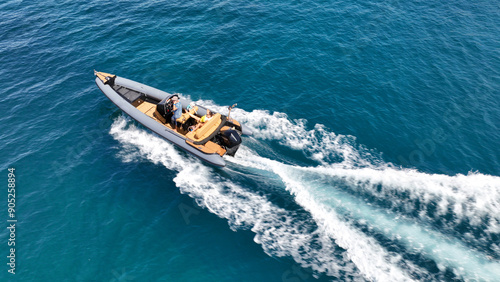 Obraz na płótnie Aerial drone high speed tracking shot of inflatable rigid power boat cruising in high speed in Mediterranean deep blue sea bay w salonie