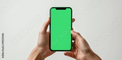 Hand holding smartphone with blank green screen, isolated on white background