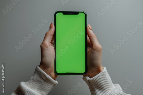 Human hand holding a smartphone with blank green screen, minimalistic design, isolated on white background. Modern tech mockup