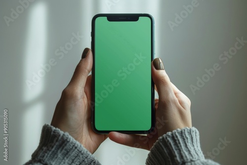Human hand holding smartphone with blank green screen, minimalistic design, white background