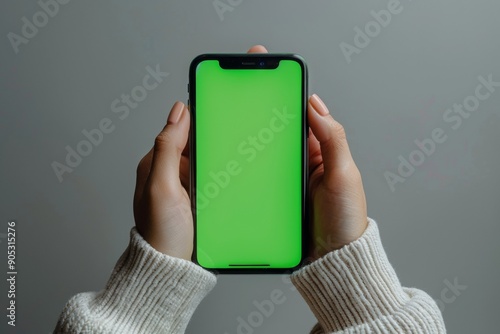 Human hand holding a smartphone with blank green screen, minimalistic design, isolated on white background. Clean tech mockup