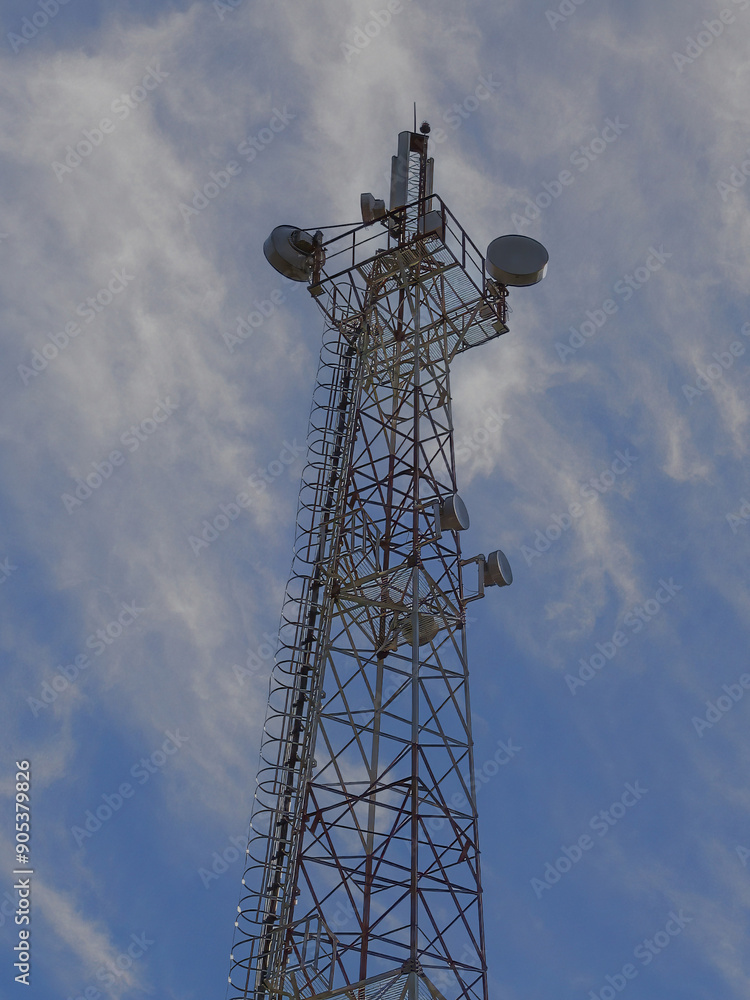 A tall communication tower against a blue sky with scattered clouds, highlighting modern technology. A tall communication tower against a blue sky with scattered clouds, highlighting modern technology.